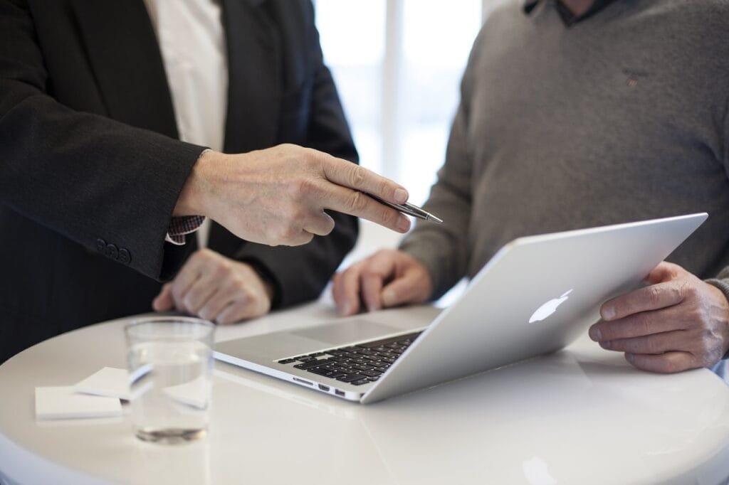 Business professionals strategizing and consulting over a laptop, making data-driven decisions.
